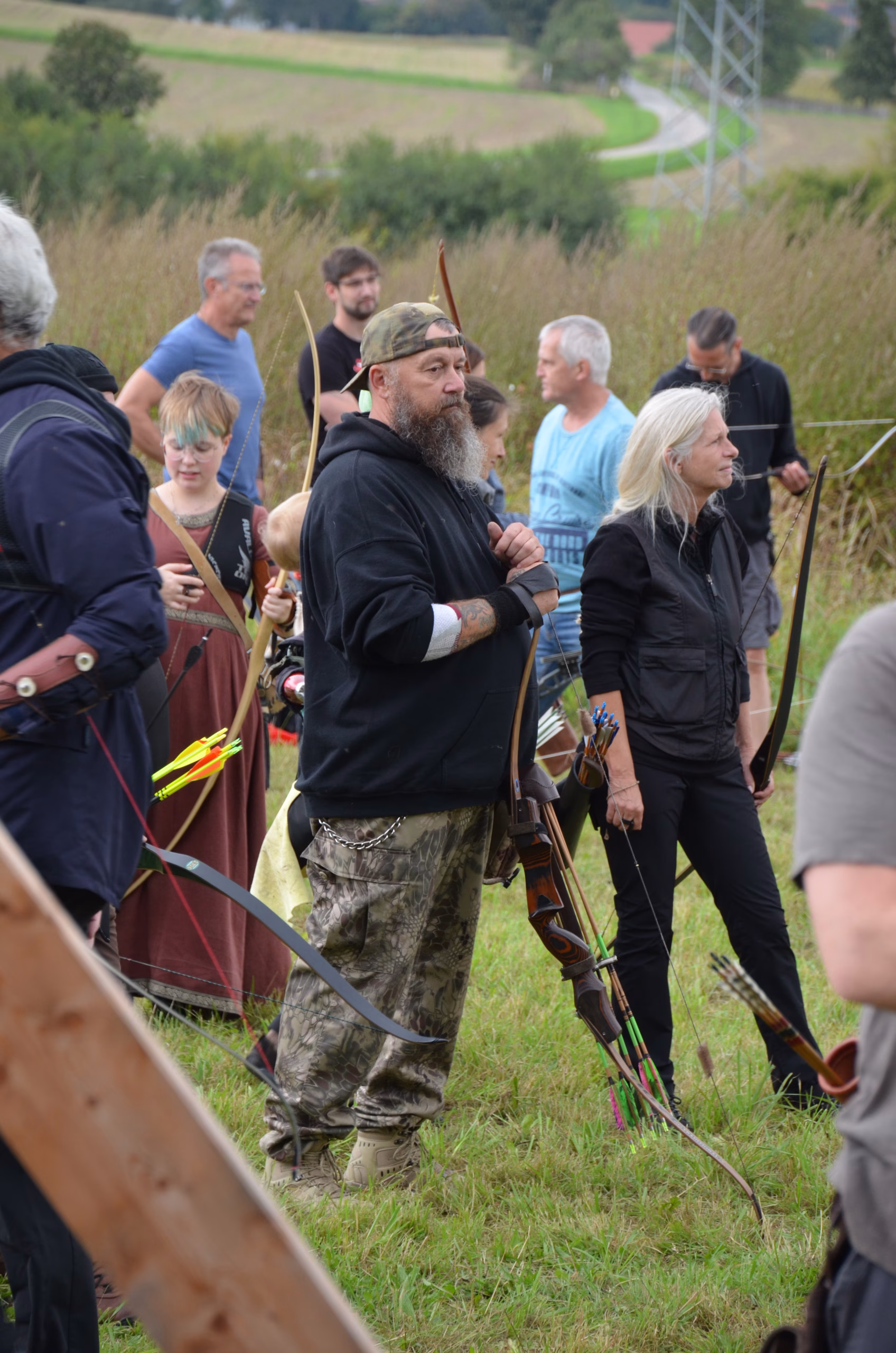 Gruppe von Bogenschützen, darunter ein Mann mit Bart und eine Frau mit blonden Haaren, beim Clout-Bogenwettbewerb 2021 in Siebenberge, veranstaltet von Pfeilflugkunst.