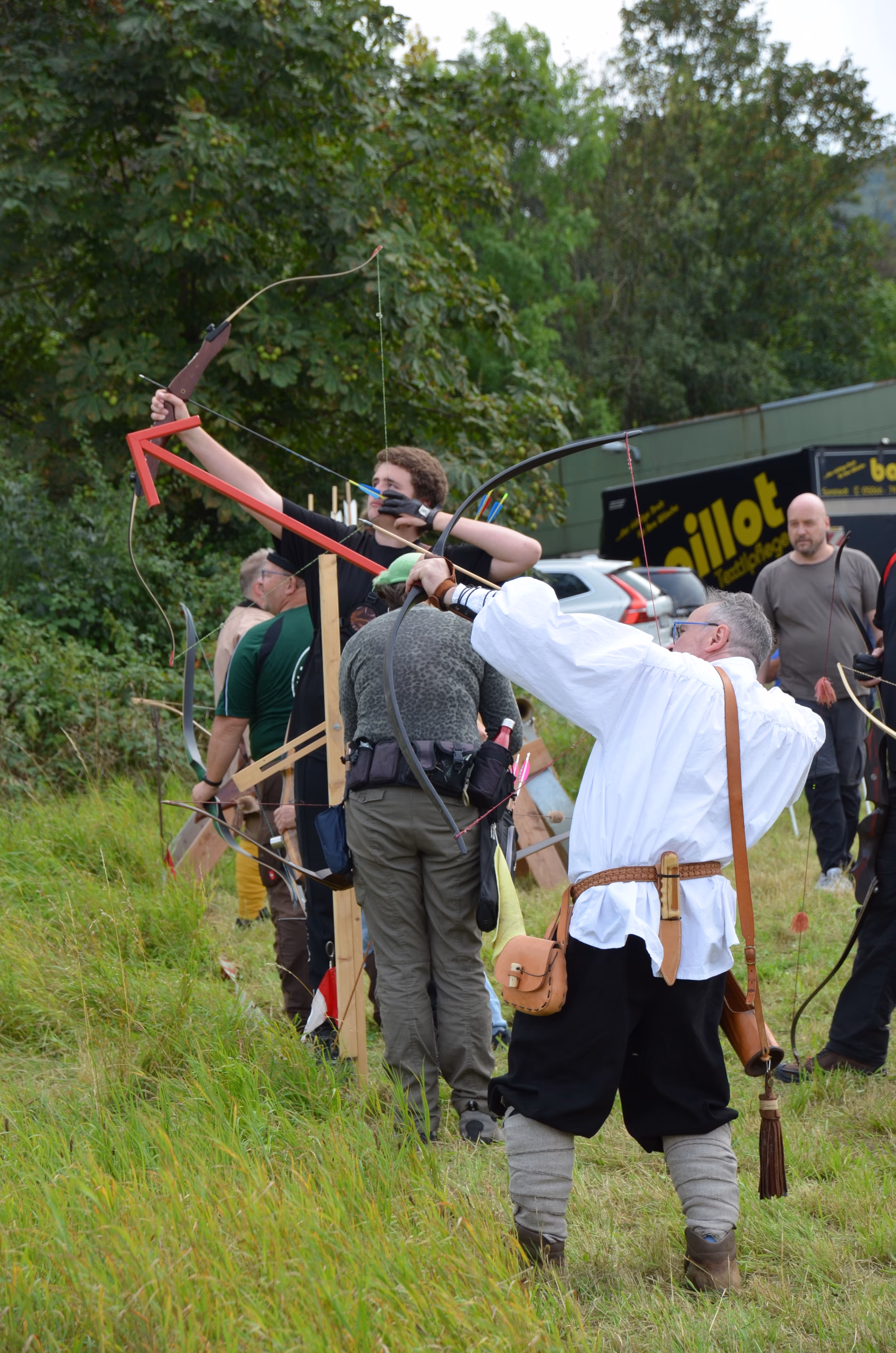 Bogenschützen beim Siebenberge Clout Bogenwettbewerb 2021 von Pfeilflugkunst, mit einem Schützen in traditioneller Kleidung, der seinen Bogen für einen Weitschuss spannt.