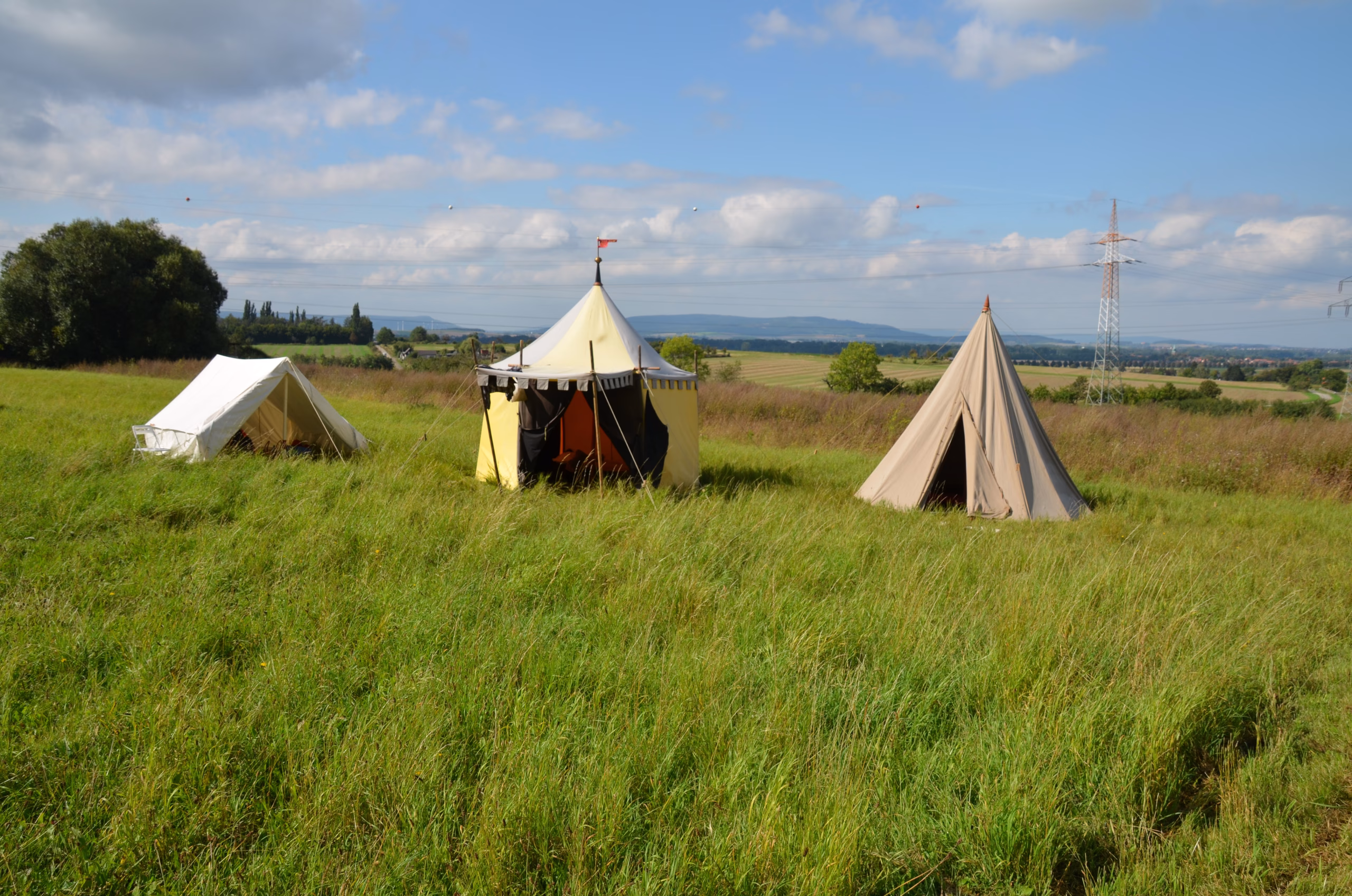 Drei traditionelle Zelte auf einem grünen Feld beim Siebenberge Clout Bogenwettbewerb von Pfeilflugkunst.