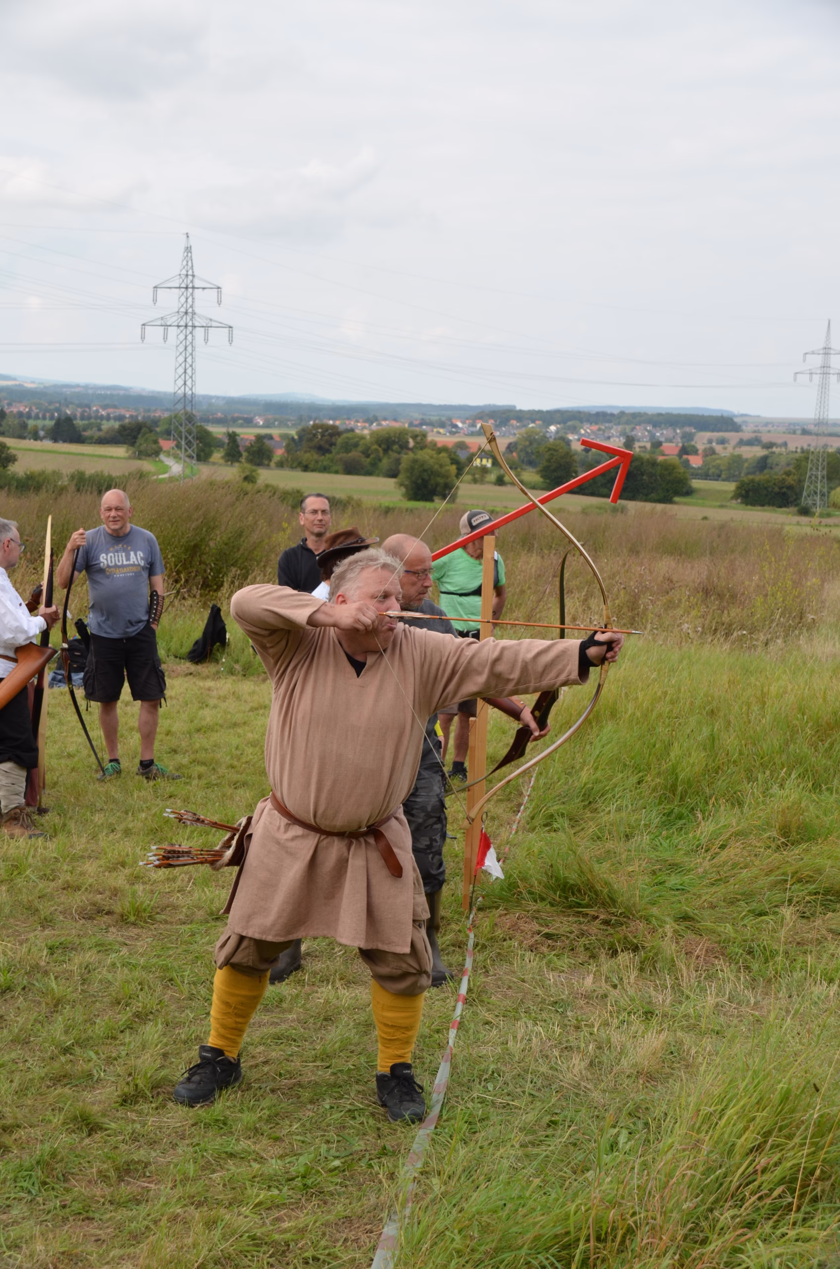 Bogenschütze in traditioneller Kleidung beim Clout-Bogenschießen des Siebenberge Clout Bogenwettbewerbs 2021, veranstaltet von Pfeilflugkunst in Siebenberge.