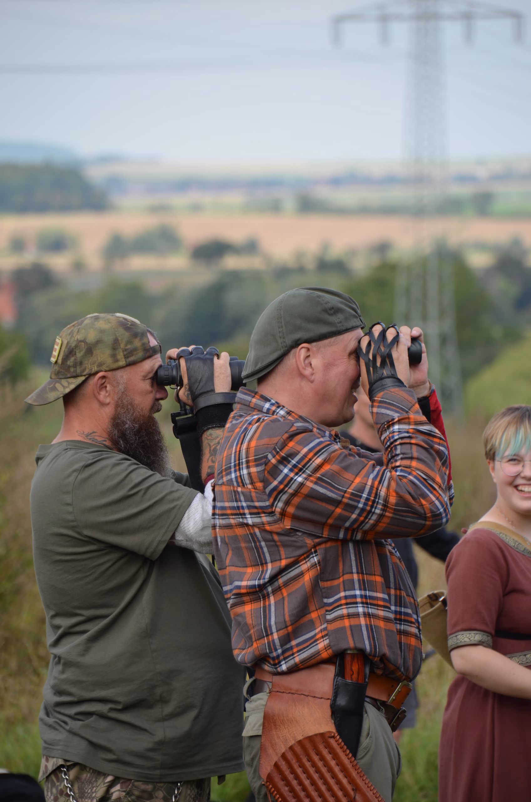 Zwei Bogenschützen beobachten mit Ferngläsern das Ziel beim Siebenberge Clout Bogenwettbewerb von Pfeilflugkunst.