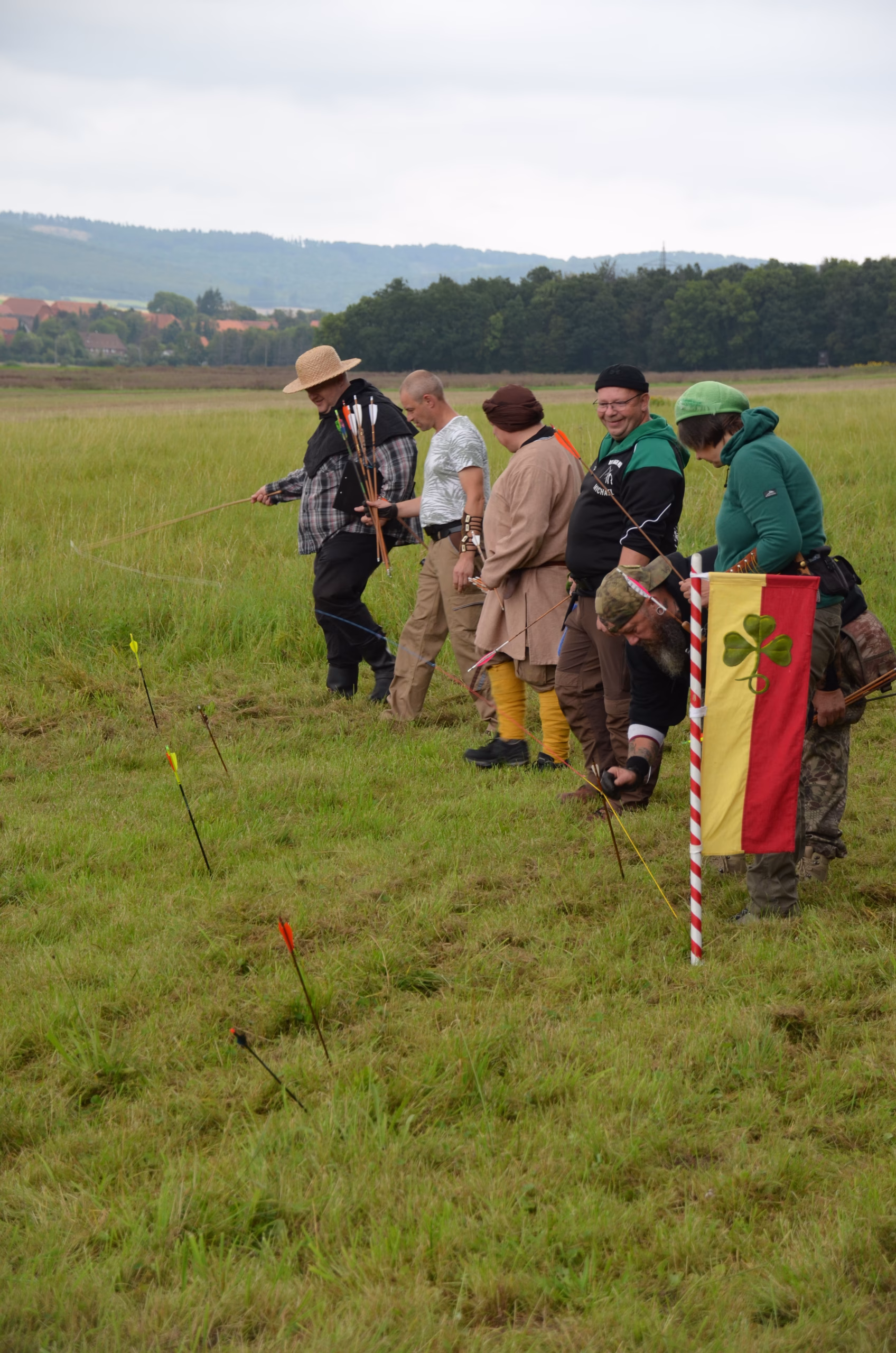 Bogenschützen beim Clout-Bogenschießen in Siebenberge, begutachten Pfeile nahe der Ziel-Flagge des Pfeilflugkunst Wettbewerbs.