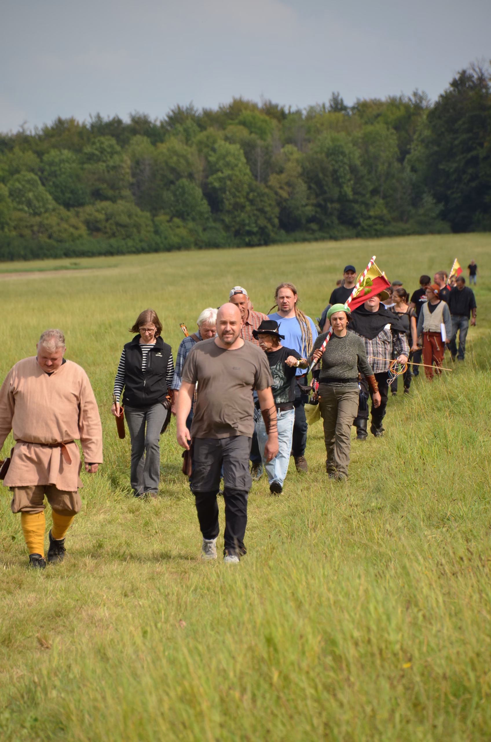 Gruppe von Bogenschützen marschiert über ein grünes Feld beim Siebenberge Clout Bogenwettbewerb 2021 von Pfeilflugkunst.