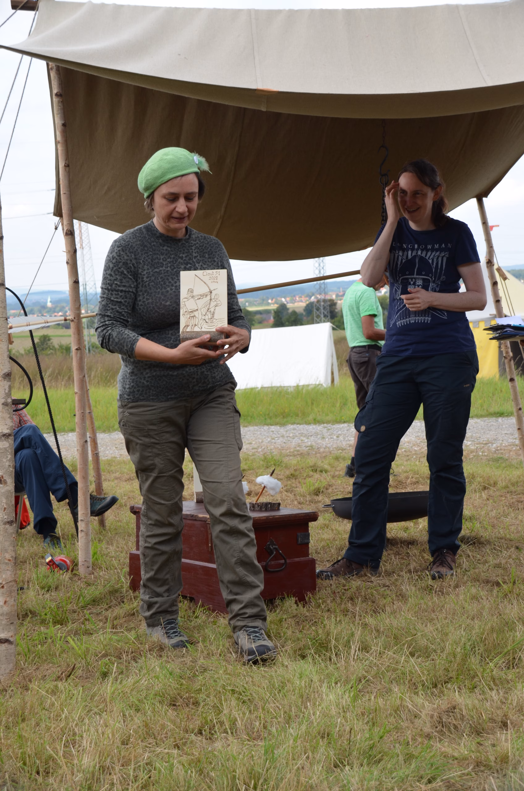 Zwei Frauen bei der Siegerehrung des Siebenberge Clout Bogenwettbewerbs 2021 von Pfeilflugkunst. Eine Frau hält eine Auszeichnung, die andere lacht.